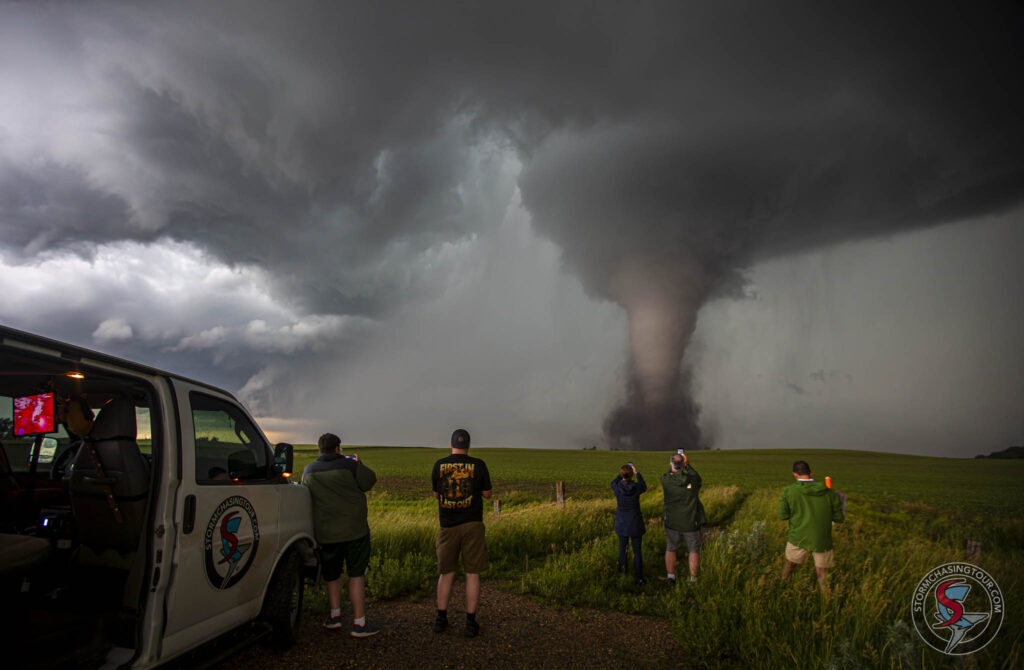 A tornado churns up the earth in front of tour guests as they film the power of Mother Nature.